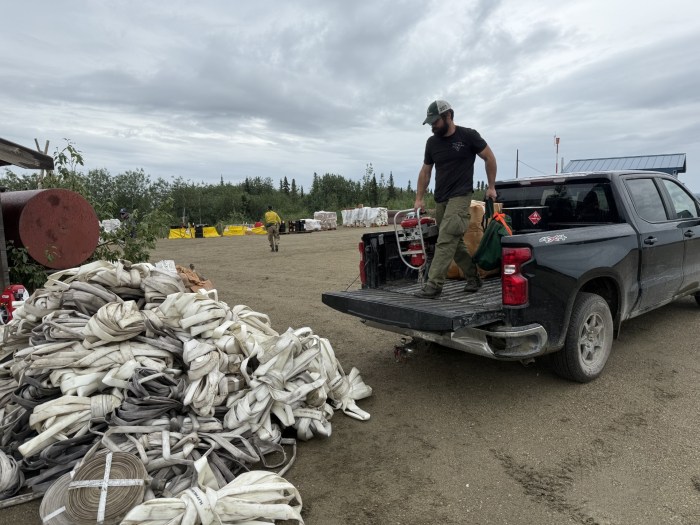 Pumps and hose are unloaded from a pickup.