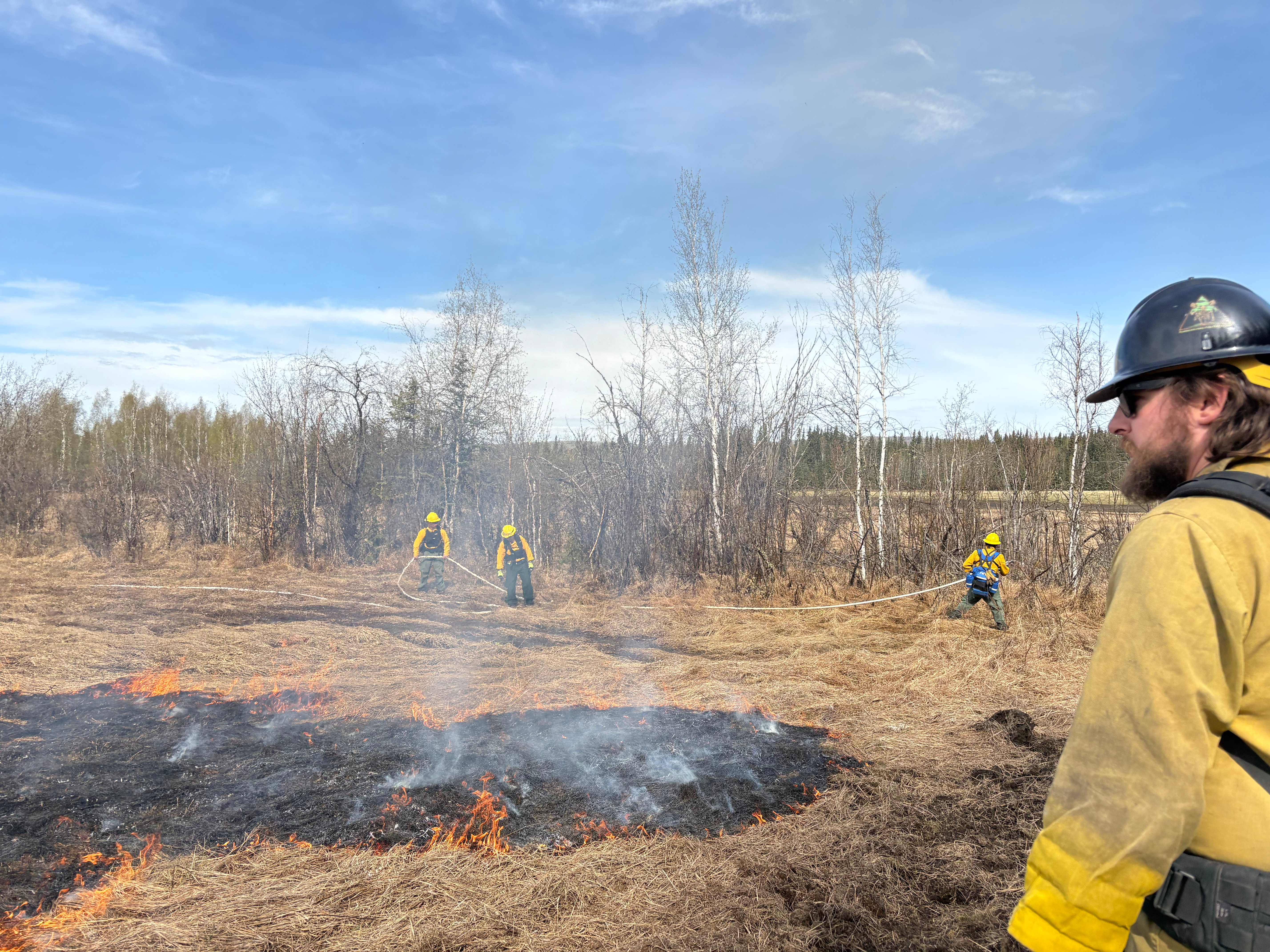 Creamers Field Echo Acres RX white Mountain Fire Crew holsing wet line and Logan Parsley, Fairbanks Area Tech supervising the fire behavior