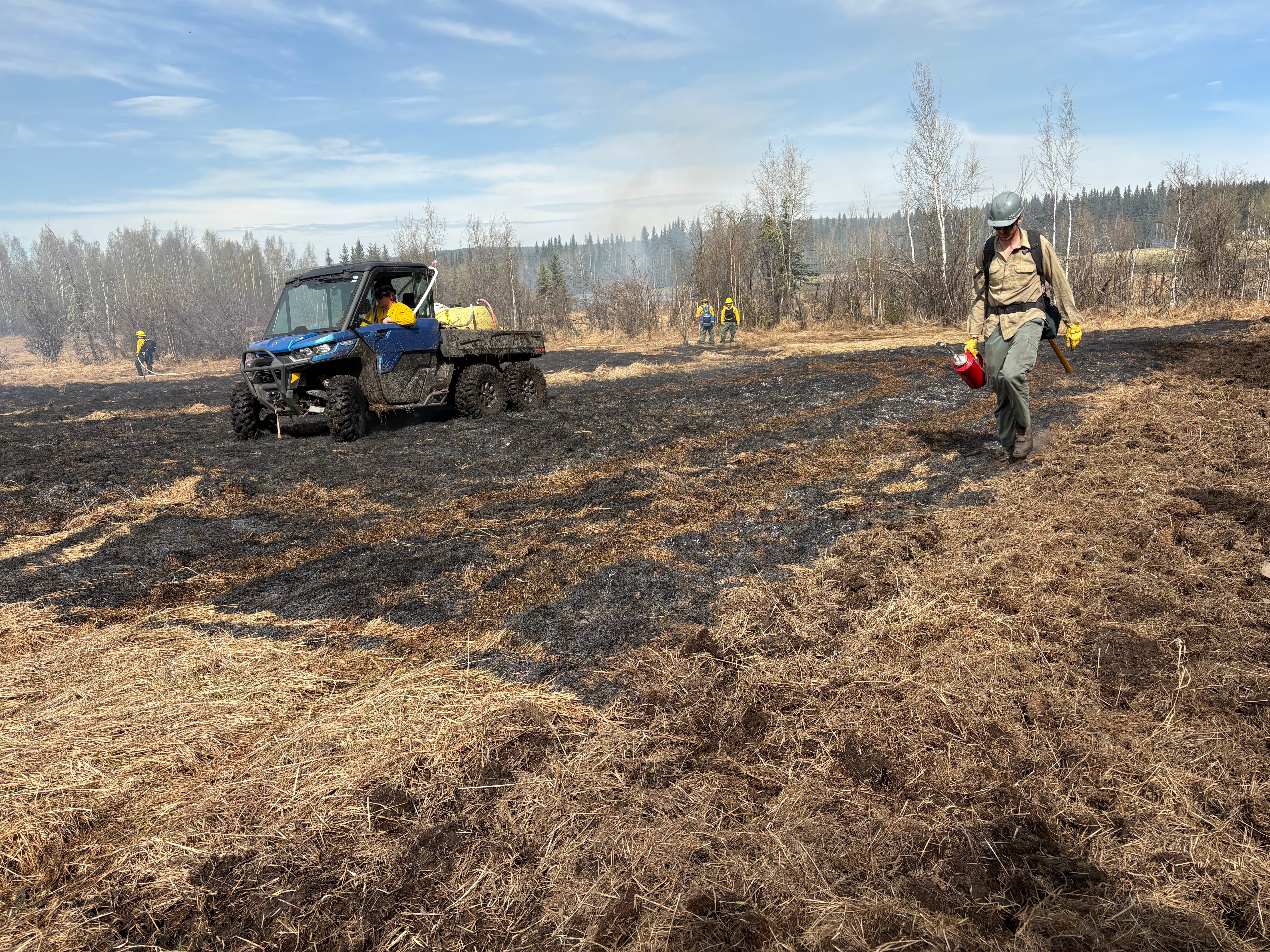 Echo Acres Creamers Field side by side with water tank per positioning while firefighter with drip torch relocates to continue the burn in the new section of grass after the test patch is complete.