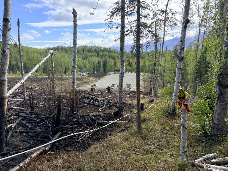 Firefighters cut saw line around fire perimeter.
