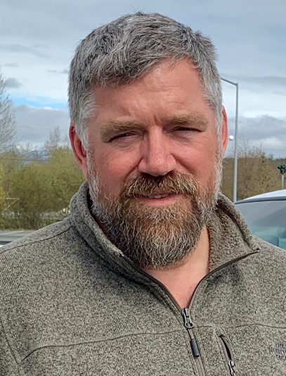 A bearded man squinting.