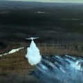This photo shows an air tanker making a water drop on a wildland fire.