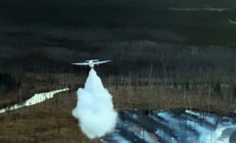 This photo shows an air tanker making a water drop on a wildland fire.