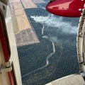 This aerial photo is looking through an aircraft's open door to a wildland fire burning below.