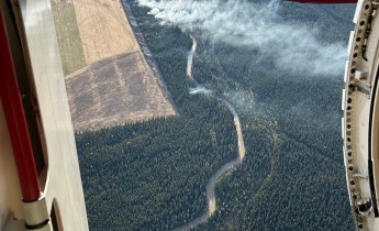 This aerial photo is looking through an aircraft's open door to a wildland fire burning below.
