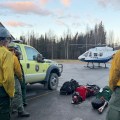 Wildland firefighters watch a landing helicopter.