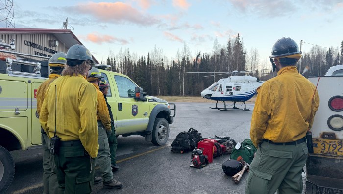 Wildland firefighters watch a landing helicopter.