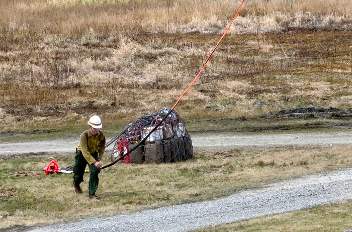 Helicopter crew member handles a helicopter's long line.