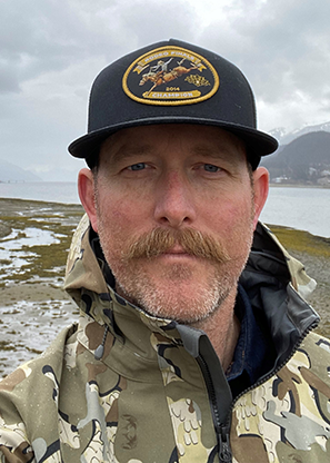 A mustached man wearing a baseball cap.