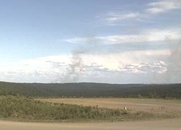 Smoke billows up from wildfires on forested hillsides.