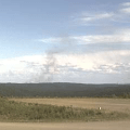 Smoke billows up from wildfires on forested hillsides.