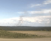 Smoke billows up from wildfires on forested hillsides.