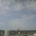 Smoke drifts up from a forest fire in in the distance. Fuel tanks are in front of the camera.