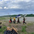4 Pioneer Peak Hotshot Crewmembers carry equipment to helicopter.