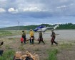 4 Pioneer Peak Hotshot Crewmembers carry equipment to helicopter.