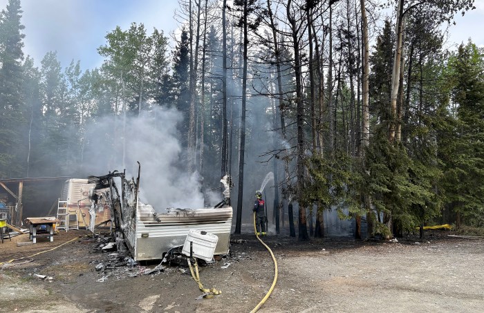 A camper trailer burned and spread to to surrounding wooded area.