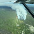 Photo from air attack plane of fire burning in black spruce alongside DFFP fuel break. Red retardant lines can be seen on north side of fire.