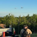 Photo of two helicopters with buckets attached with long lines.
