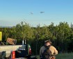 Photo of two helicopters with buckets attached with long lines.