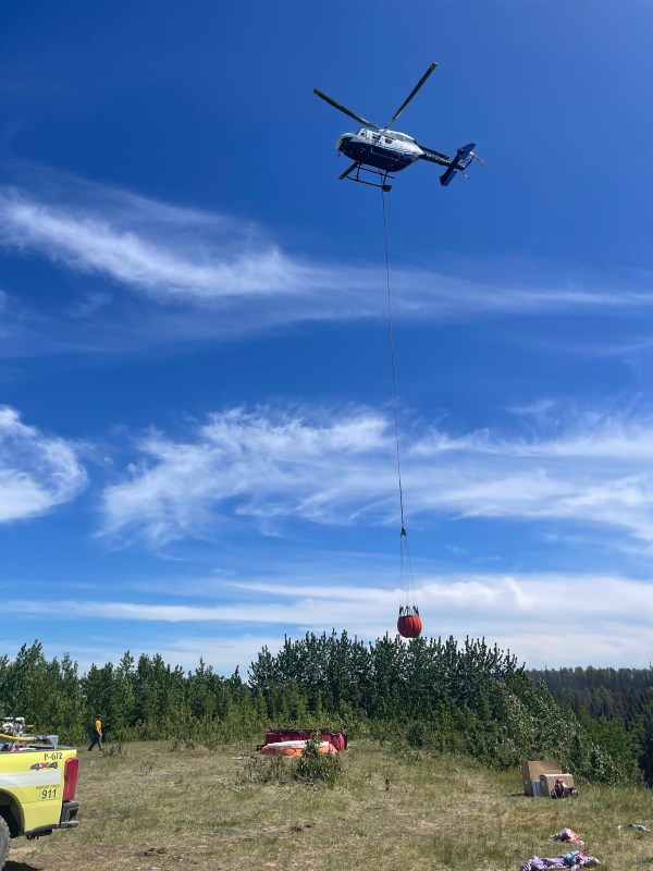 Photo of helicopter with bucket attached by long line.
