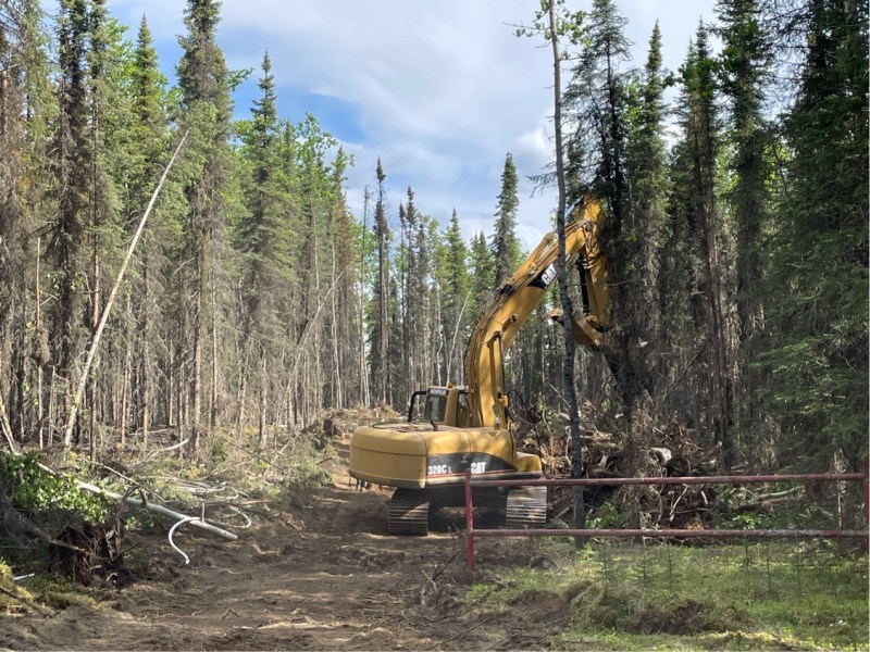 Excavator removing hazardous trees along fire perimeter.