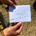 Photo of firefighter holding white envelope that reads "Thank you to all the Grandview firefighters + crew!" with a heart.