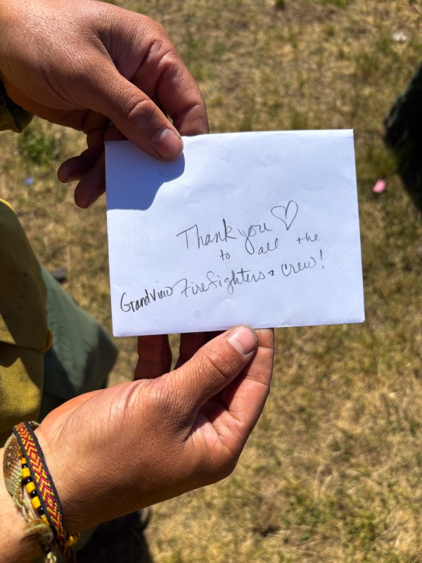 Photo of firefighter holding white envelope that reads "Thank you to all the Grandview firefighters + crew!" with a heart.