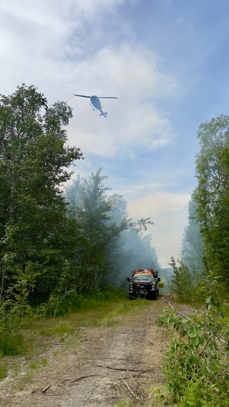 Phot of DFFP engine parked in easement, while helicopter with bucket flies overhead.