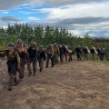 Firefighters carrying gear and equipment, walking back to camp in a line.