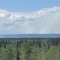 Smoke drifts up from a forest fire in the distance.