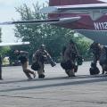 Smokejumpers dressed in fire jumpsuits and helmets carry gear to board CASA aircraft to depart for initial attack.