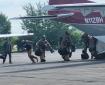 Smokejumpers dressed in fire jumpsuits and helmets carry gear to board CASA aircraft to depart for initial attack.