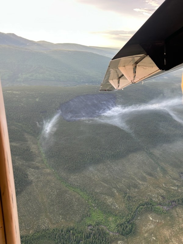 Aerial view of smoke rising from the Truce Fire on a steep hillside. An airplane wingtip is visible on the left side of the photo.