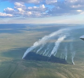 Partly cloudy skies above smoke columns rising from burned area of the Chotzatdhah Fire on June 21, 2026.