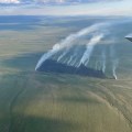 Partly cloudy skies above smoke columns rising from burned area of the Chotzatdhah Fire on June 21, 2026.