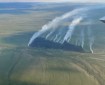 Partly cloudy skies above smoke columns rising from burned area of the Chotzatdhah Fire on June 21, 2026.