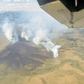 Smoke billows up from a large tundra fire as seen from an airplane.