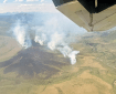 Smoke billows up from a large tundra fire as seen from an airplane.
