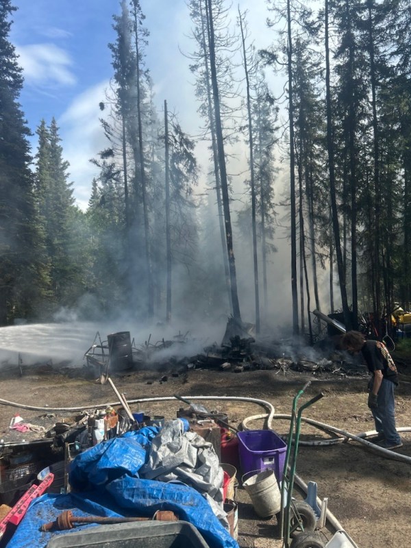 Photo of remnants of burned house surrounded by burned trees.