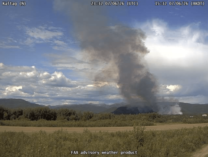 A large smoke column rises up from the ground in the distance.